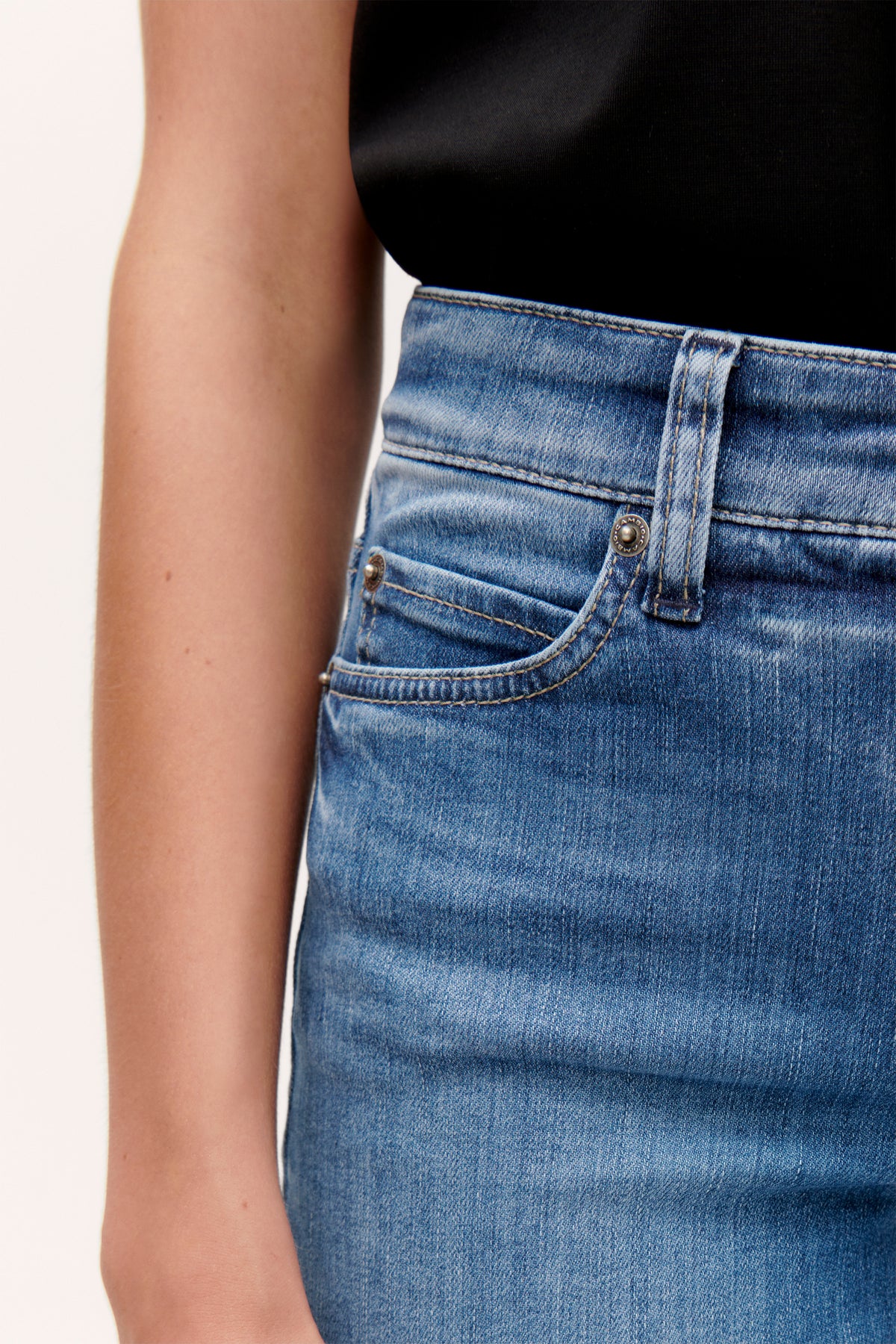 Blaue Flared-Jeans aus Bio-Baumwolle mit zwei Seitentaschen, getragen in einem legeren, alltäglichen Setting.